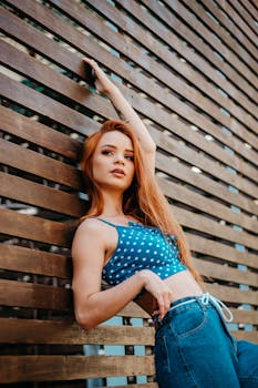 一位年轻时尚的女子在户外木制背景前摆出姿势，展现夏日风情