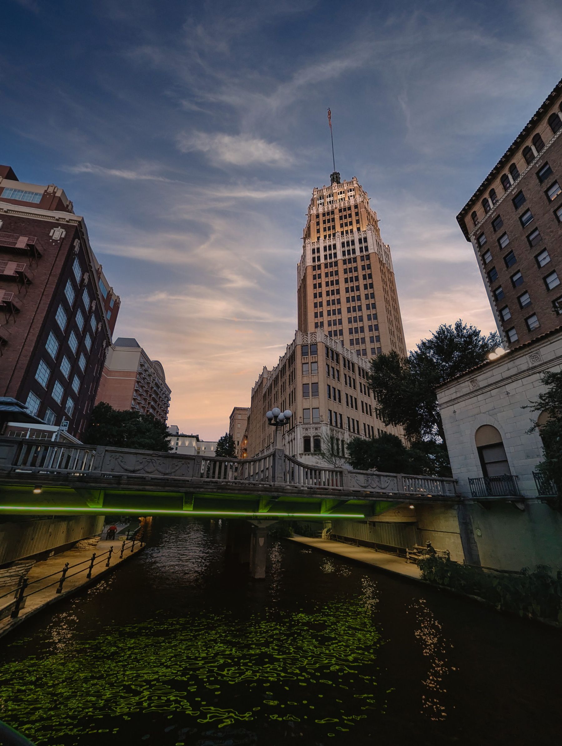 Historic Tower Life Building and the San Antonio River Walk bridge at dusk