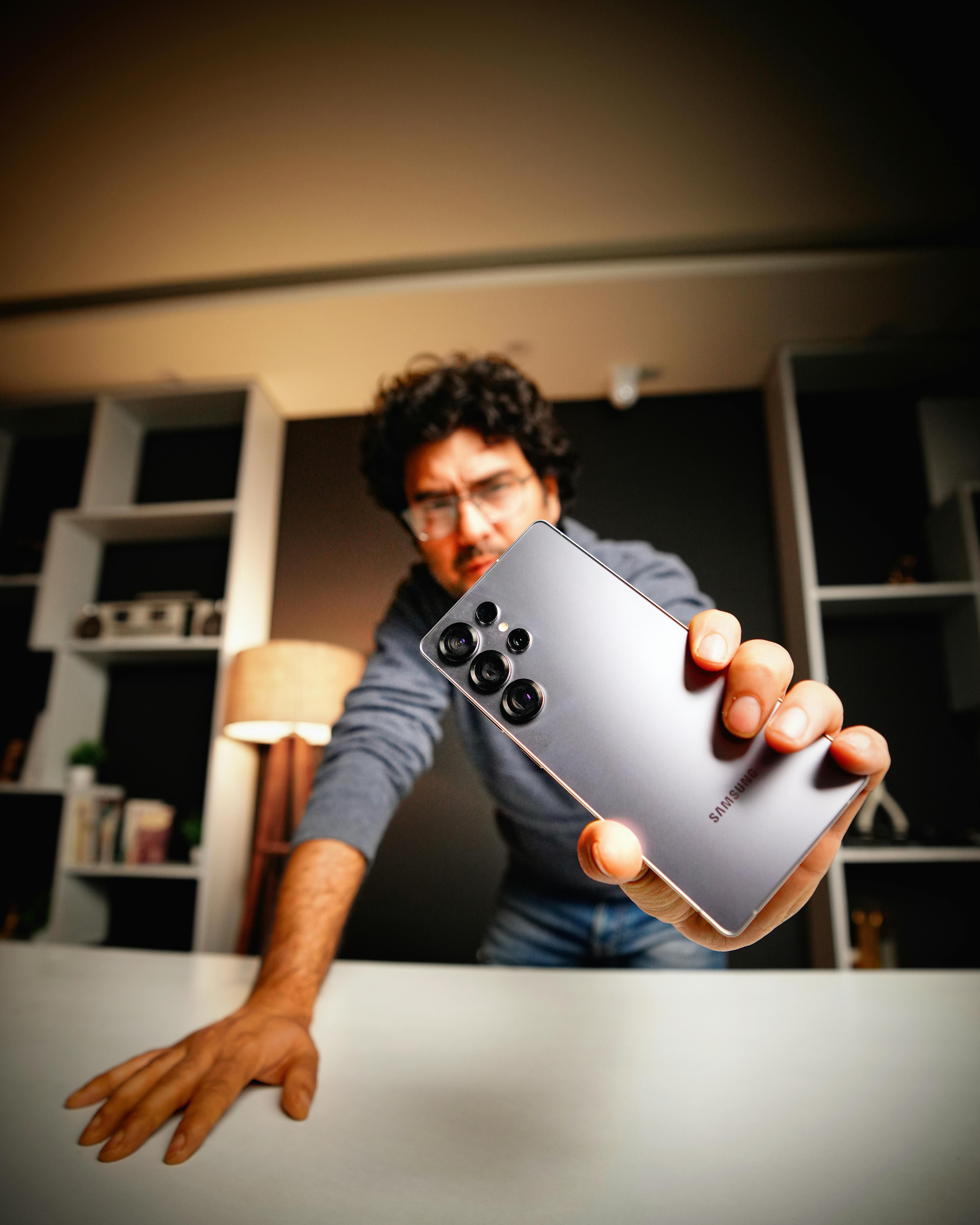 Free A person displays a Samsung smartphone in a contemporary interior setting. Stock Photo