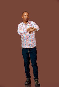 Adult man in colorful shirt checking his smartwatch, standing against a plain background.