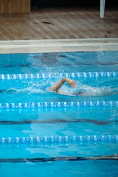 A swimmer practicing freestyle stroke in an indoor swimming pool