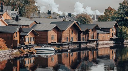 Free Charming wooden houses along Porvoo's riverbank reflect in tranquil water, showcasing Finnish architecture. Stock Photo