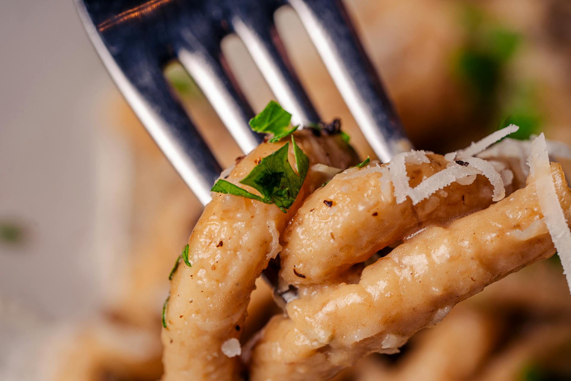 Delicious Italian pasta topped with Parmesan cheese and fresh herbs on a fork. Perfect for gourmet cooking and dining themes.