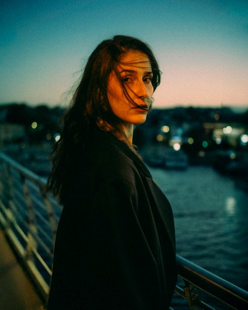 Free Captivating portrait of a woman on a waterfront during sunset, evoking a moody and serene atmosphere. Stock Photo