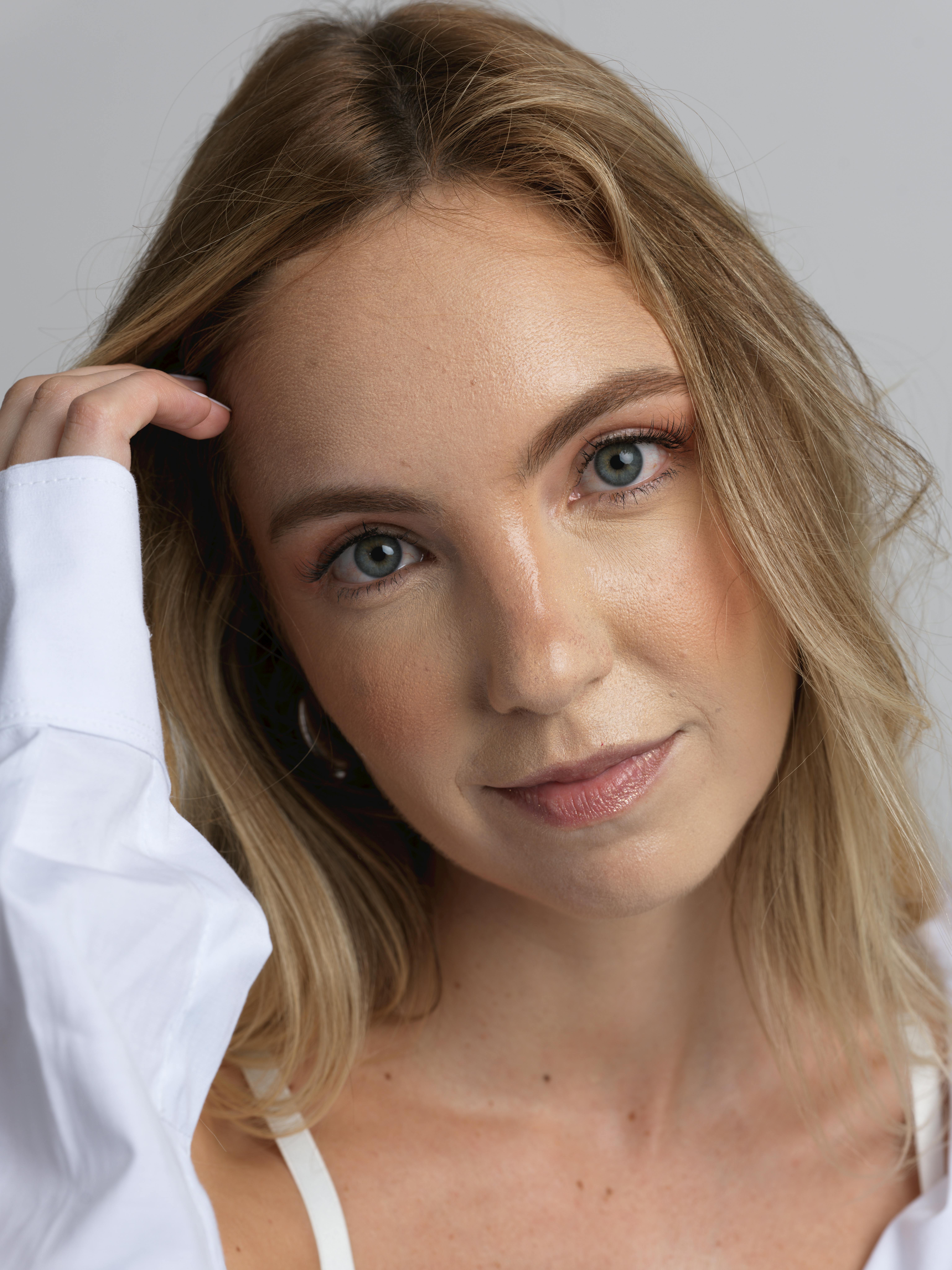 Close-up portrait of a young woman with blonde hair and blue eyes in natural light.