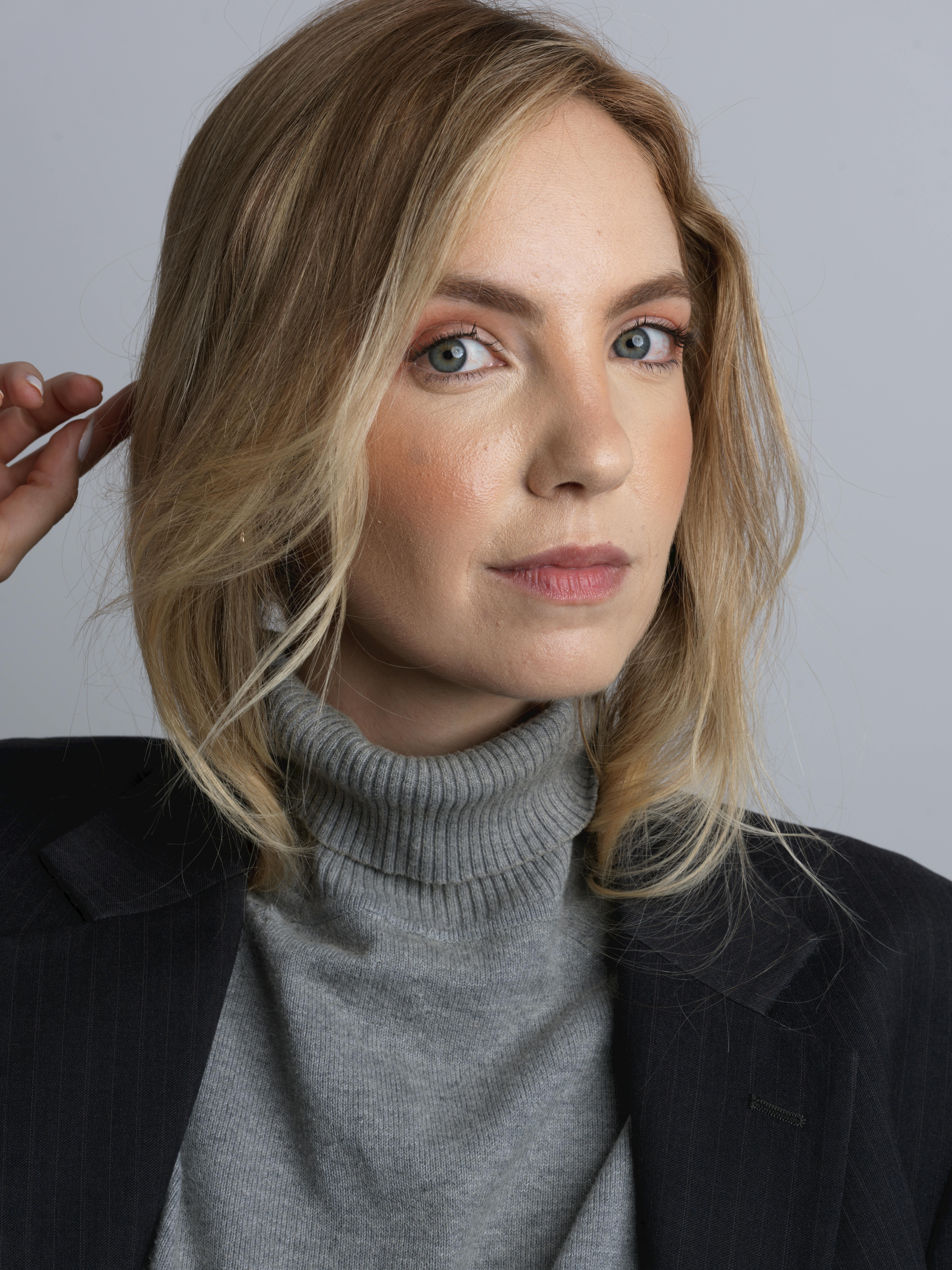 Stylish portrait of a woman in a gray turtleneck and black blazer, ideal for fashion and lifestyle themes.
