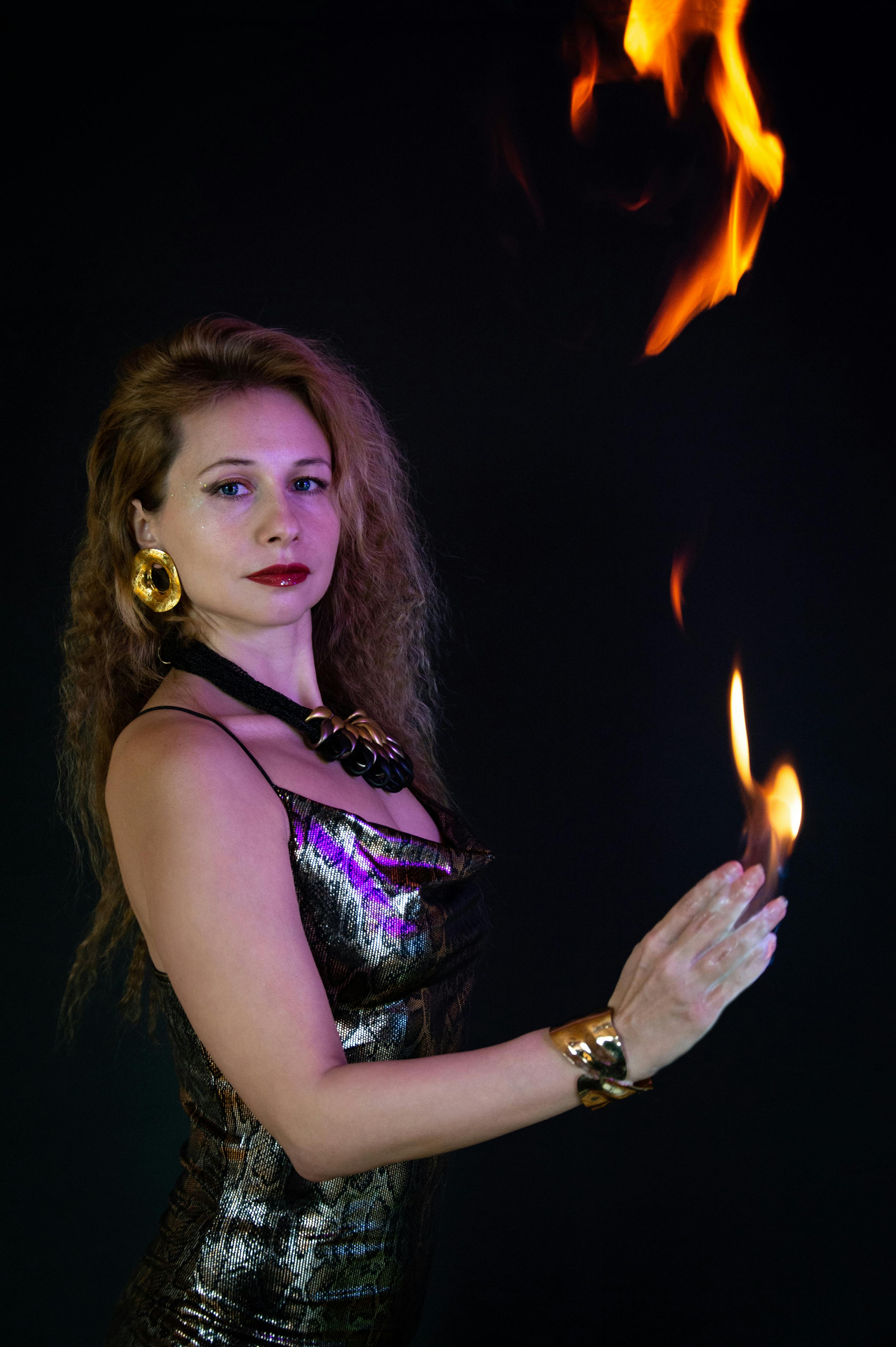 Elegant woman in a metallic dress performing a fire dance with skill and grace.