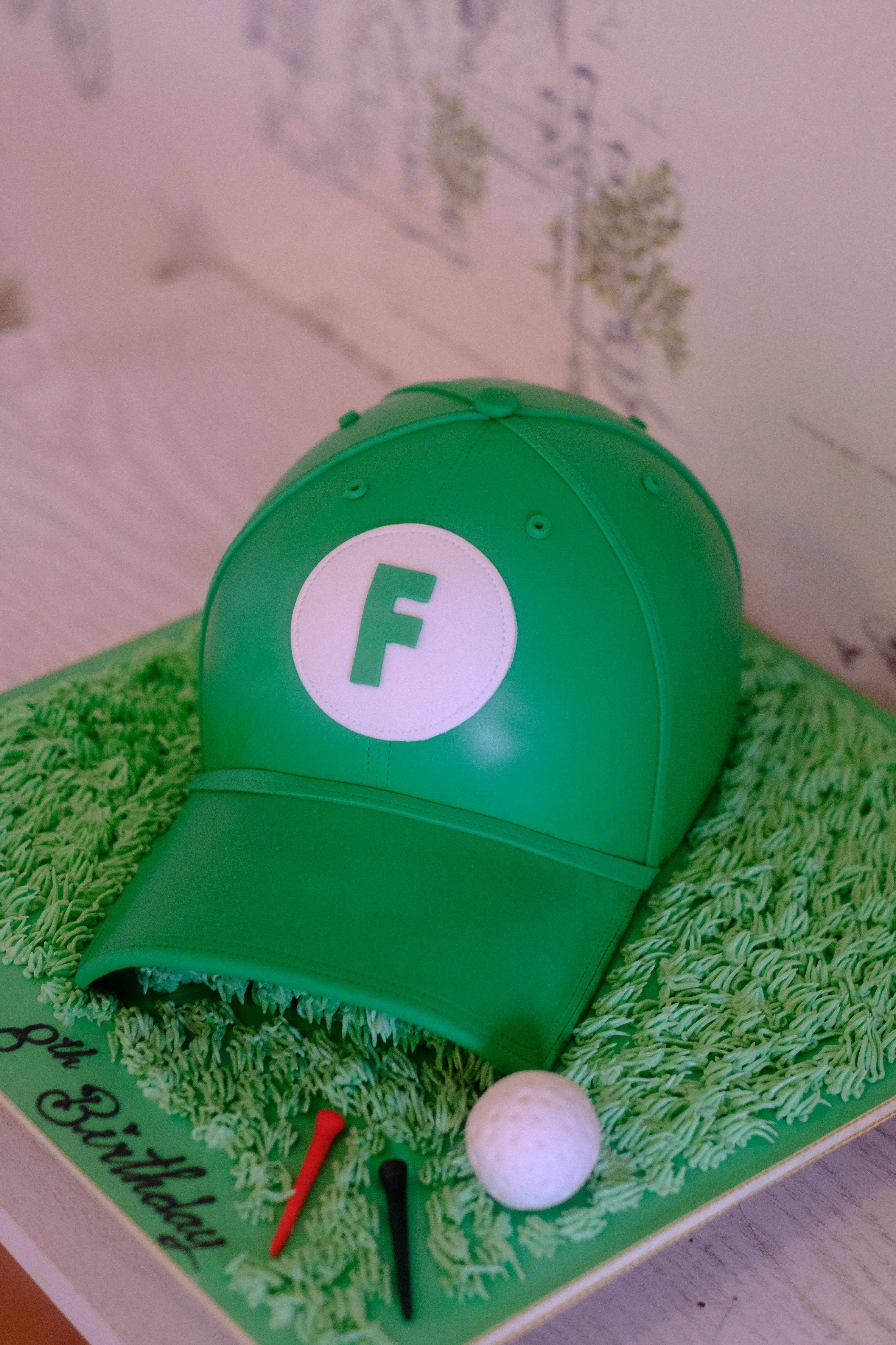 Creative birthday cake resembling a green cap with golf theme elements.