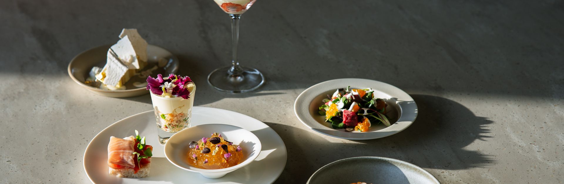 Handcrafted gourmet dishes elegantly presented under natural light on a luxurious dining table.