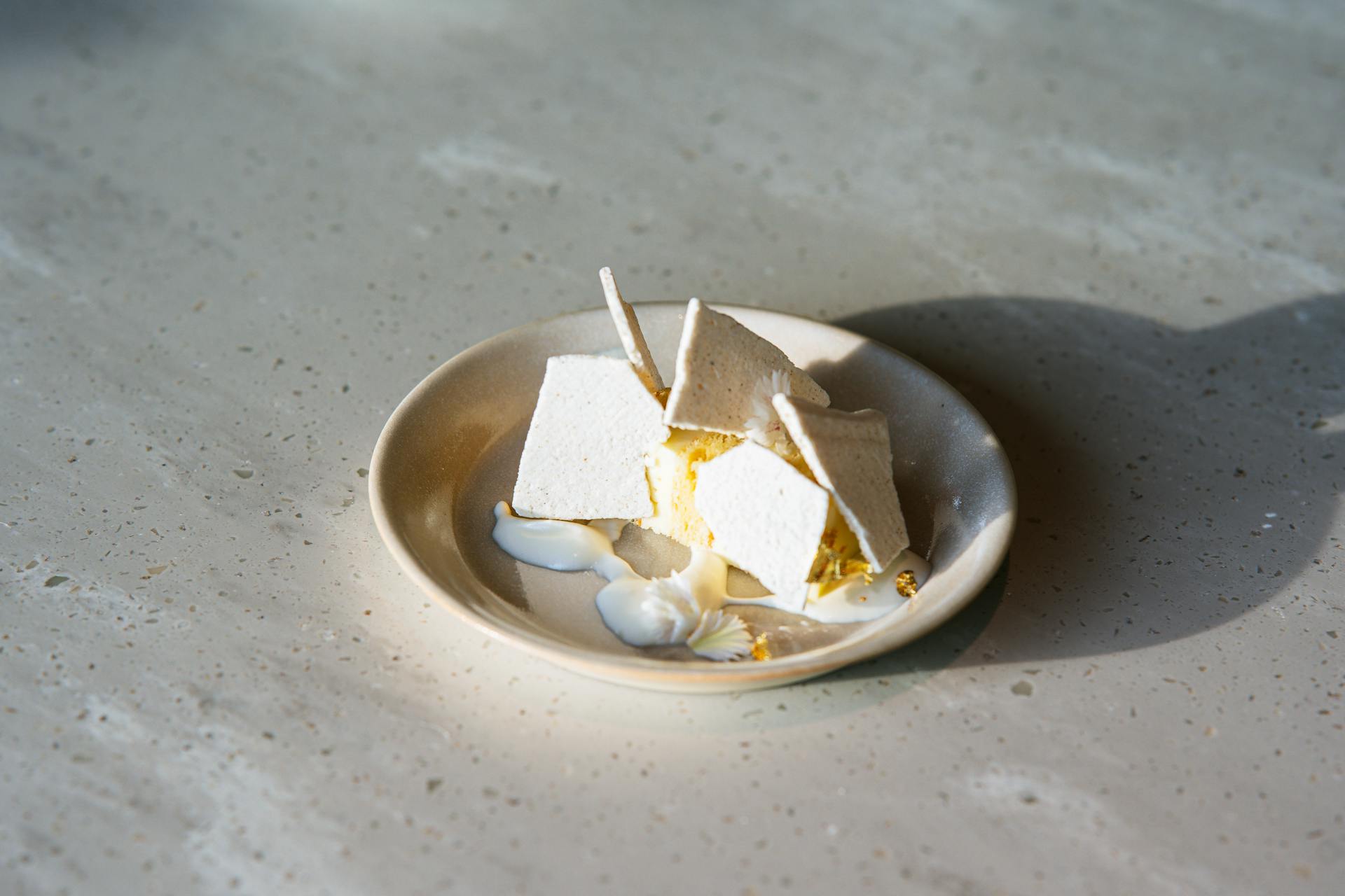 A beautifully arranged dessert on a plate, showcasing artistic food presentation in soft natural light.