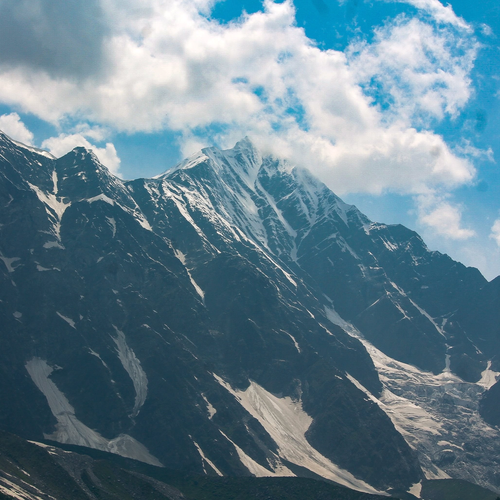 Free A breathtaking view of snow-capped mountains under blue skies with clouds. Stock Photo