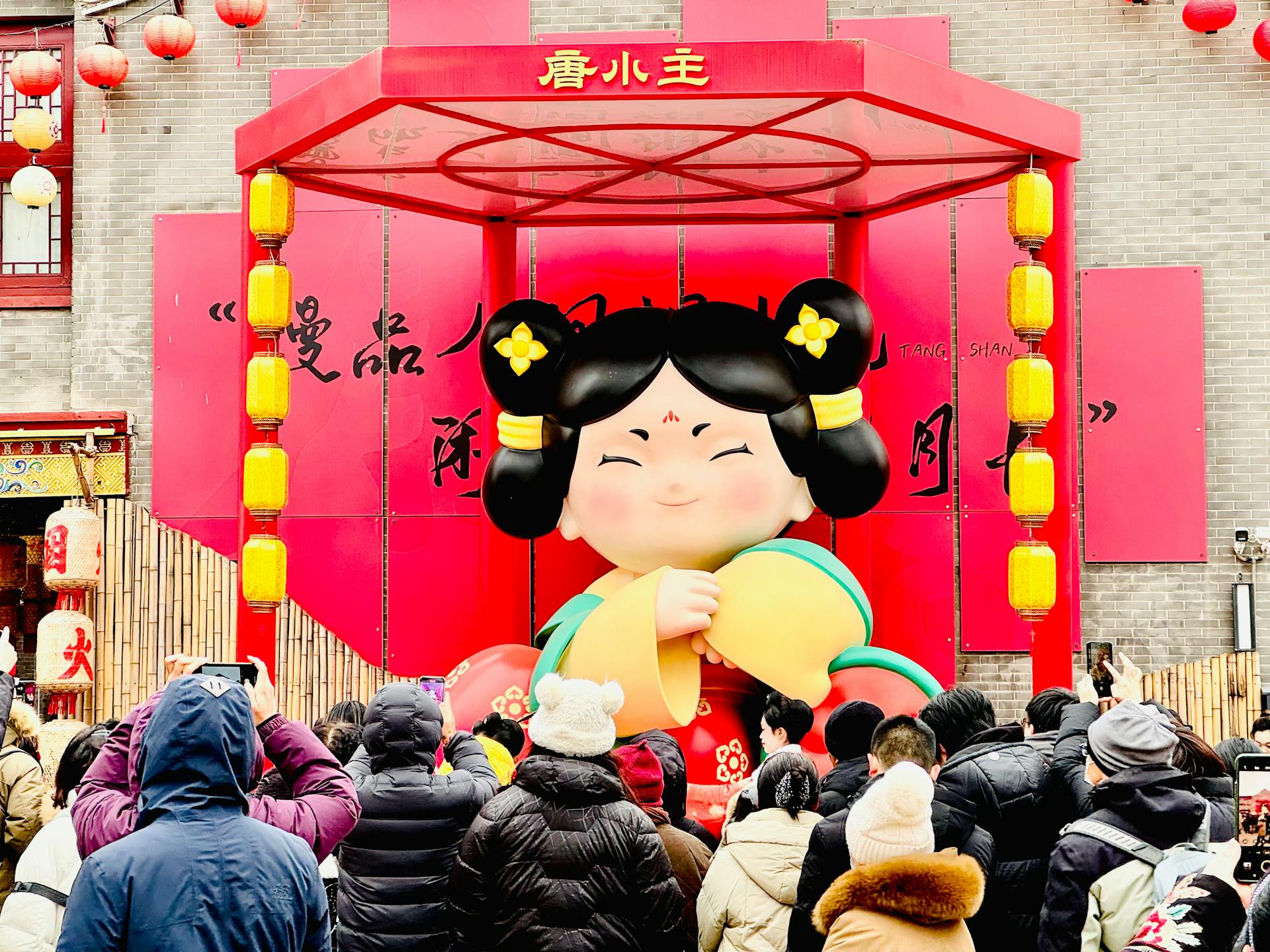 Vibrant festival scene with large decorative Asian statue and crowd outdoors.
