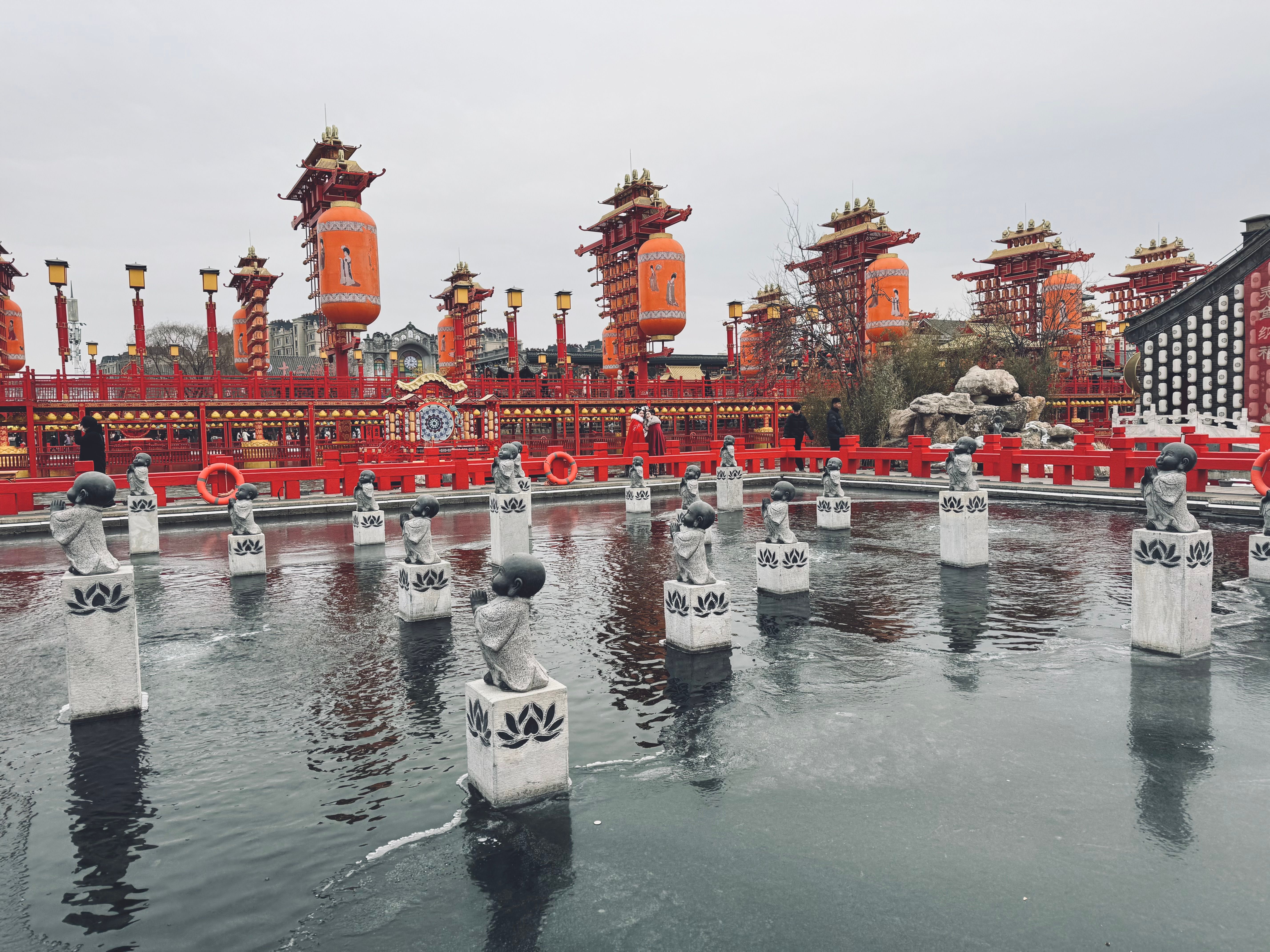 Vibrant traditional Chinese architecture and lanterns with water feature statues create a festive cultural scene.