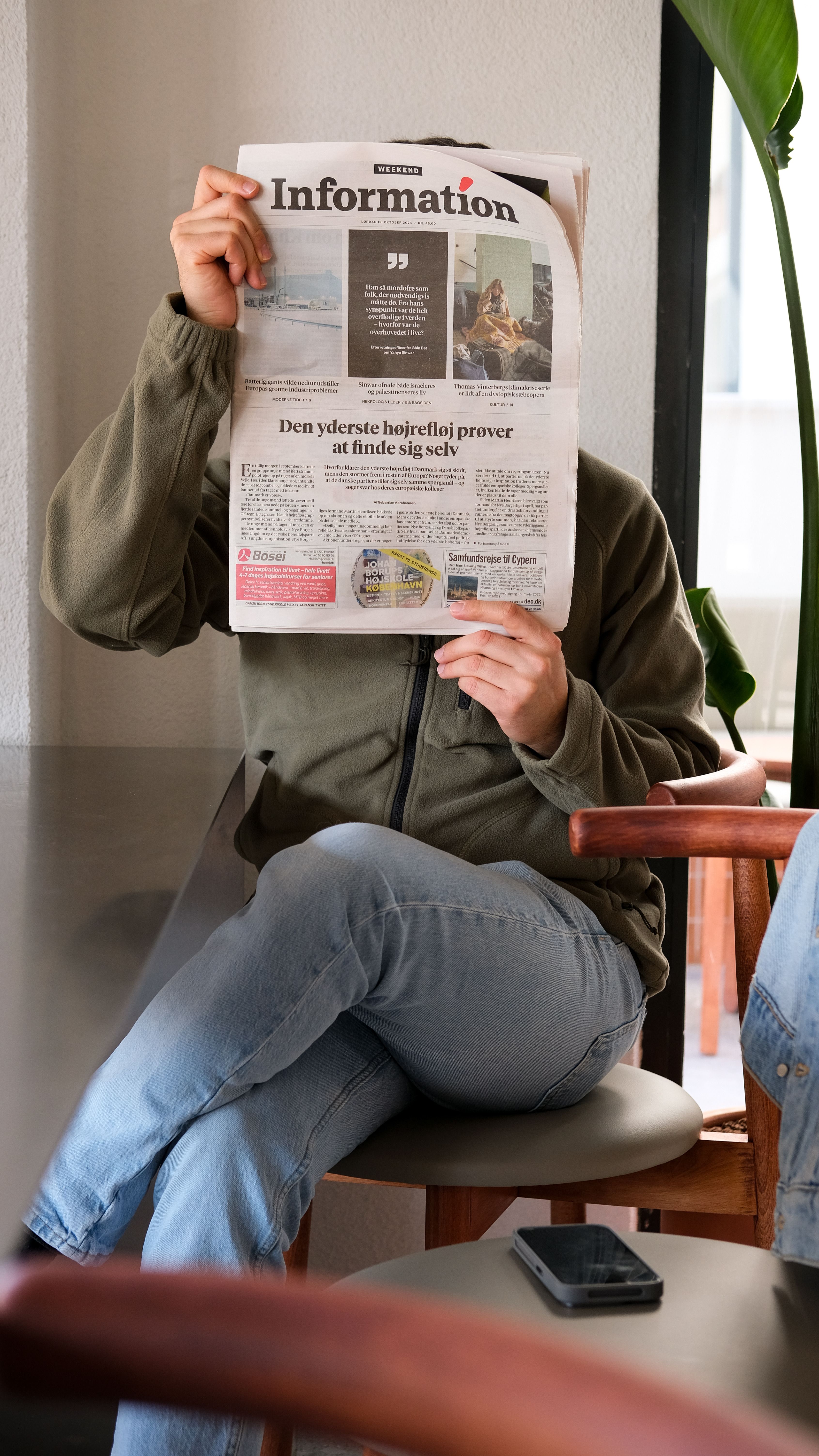 Casual setting with a person reading a newspaper in a modern cafe.
