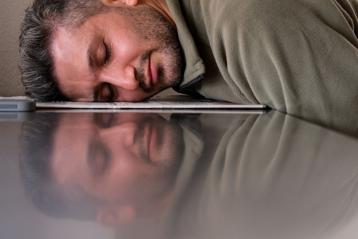 Tired man resting his head on a laptop after a long desk day