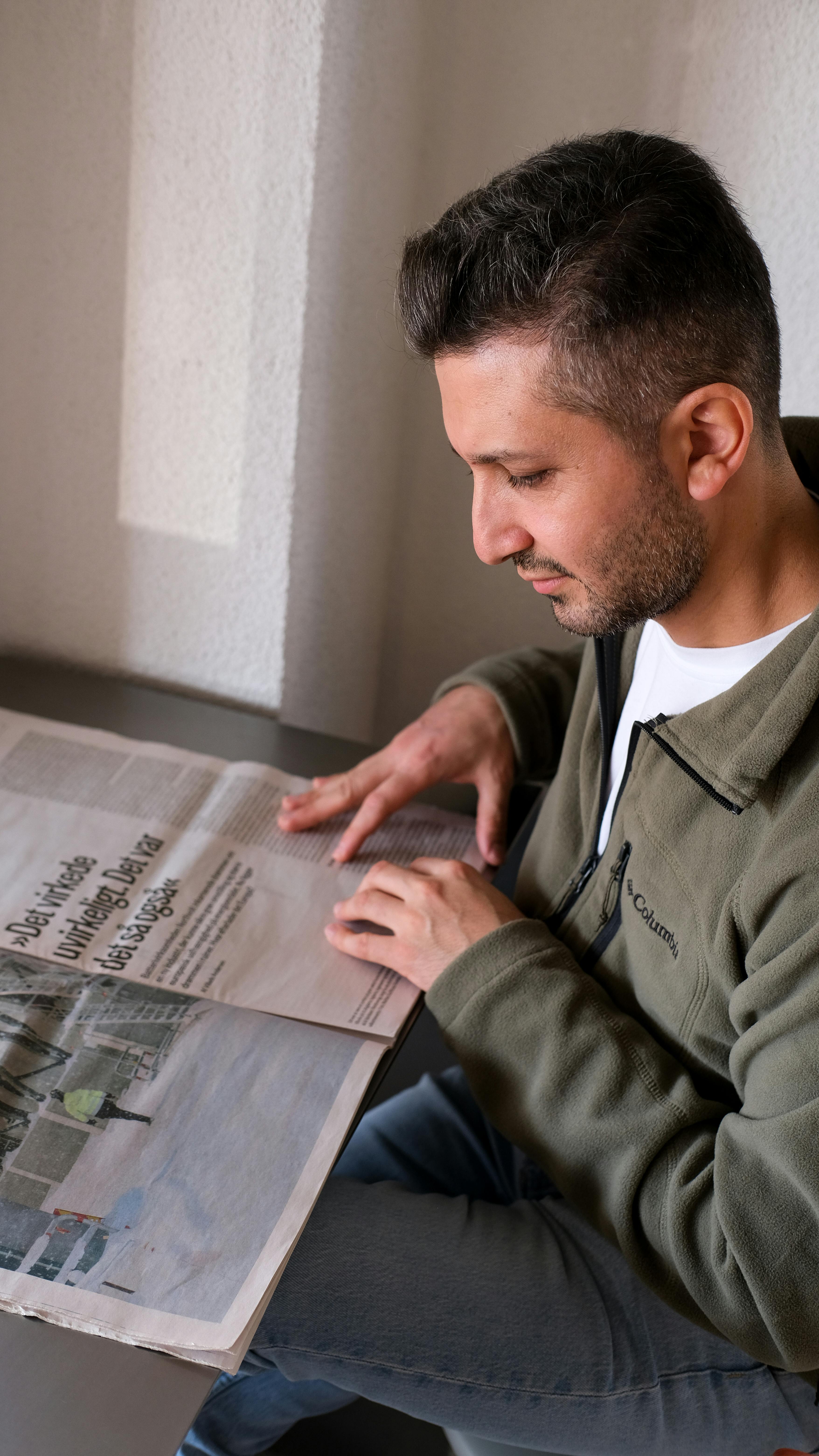 man reading newspaper indoors at table