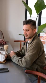 A man enjoys coffee while seated at a modern cafe in Istanbul, Türkiye.