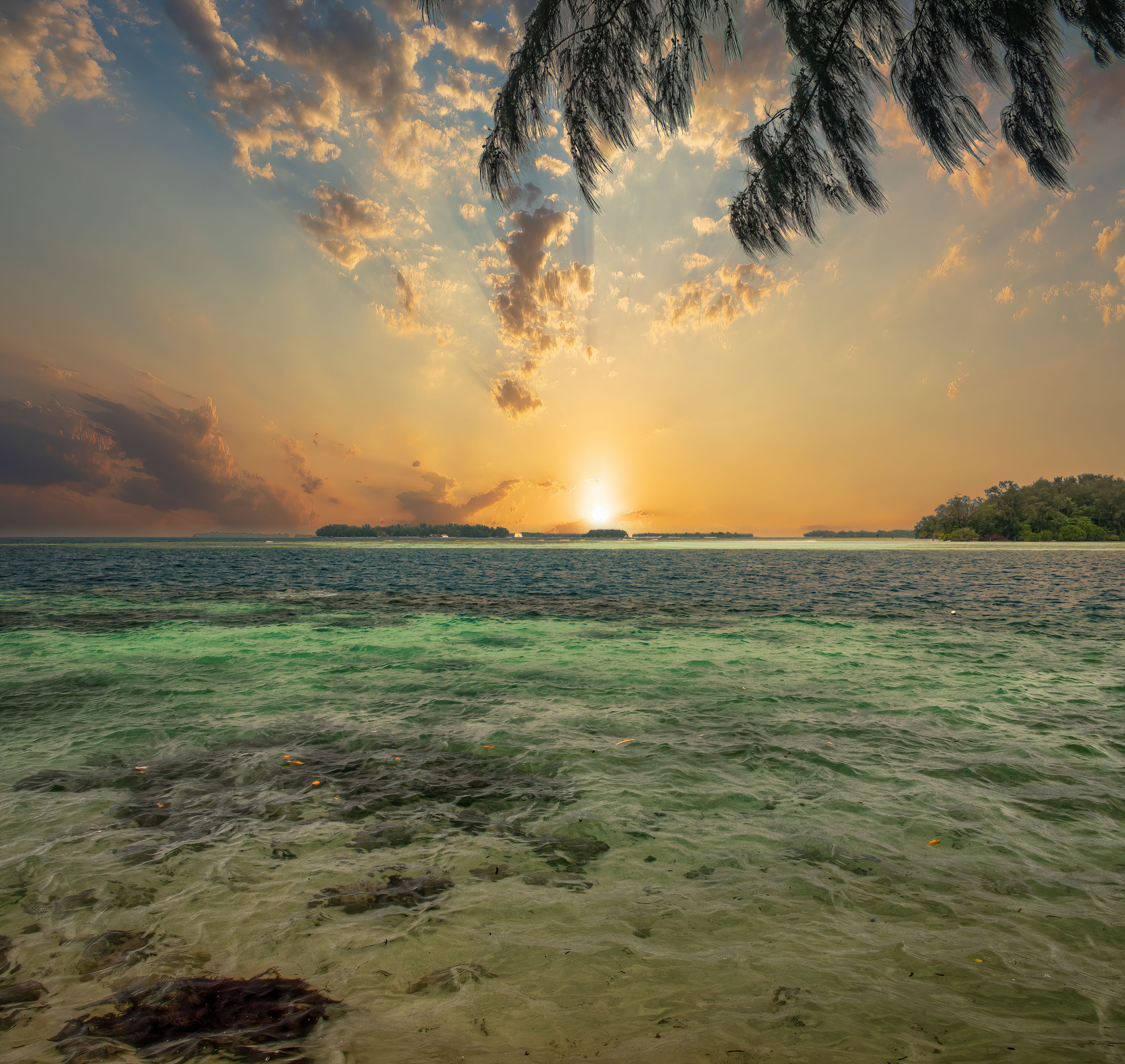 Vue paisible du lever du soleil sur l'océan depuis Jakarta, en Indonésie, avec un ciel vibrant et des eaux calmes.