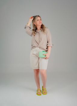 Stylish adult woman in casual beige attire holding a green purse indoors.