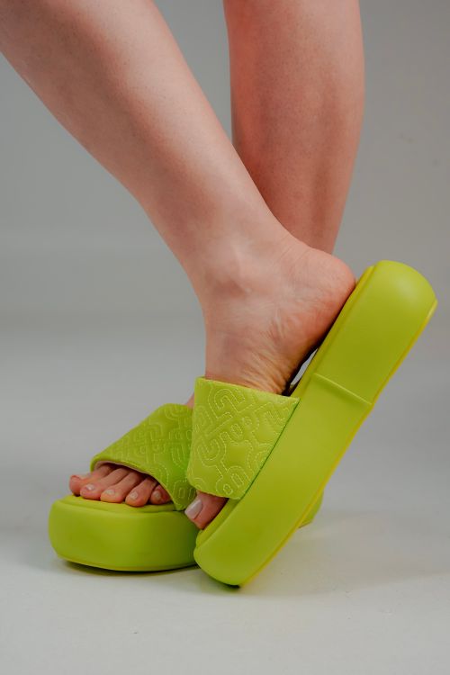 Free Close-up of stylish green slide sandals worn on feet, highlighting summer fashion. Stock Photo