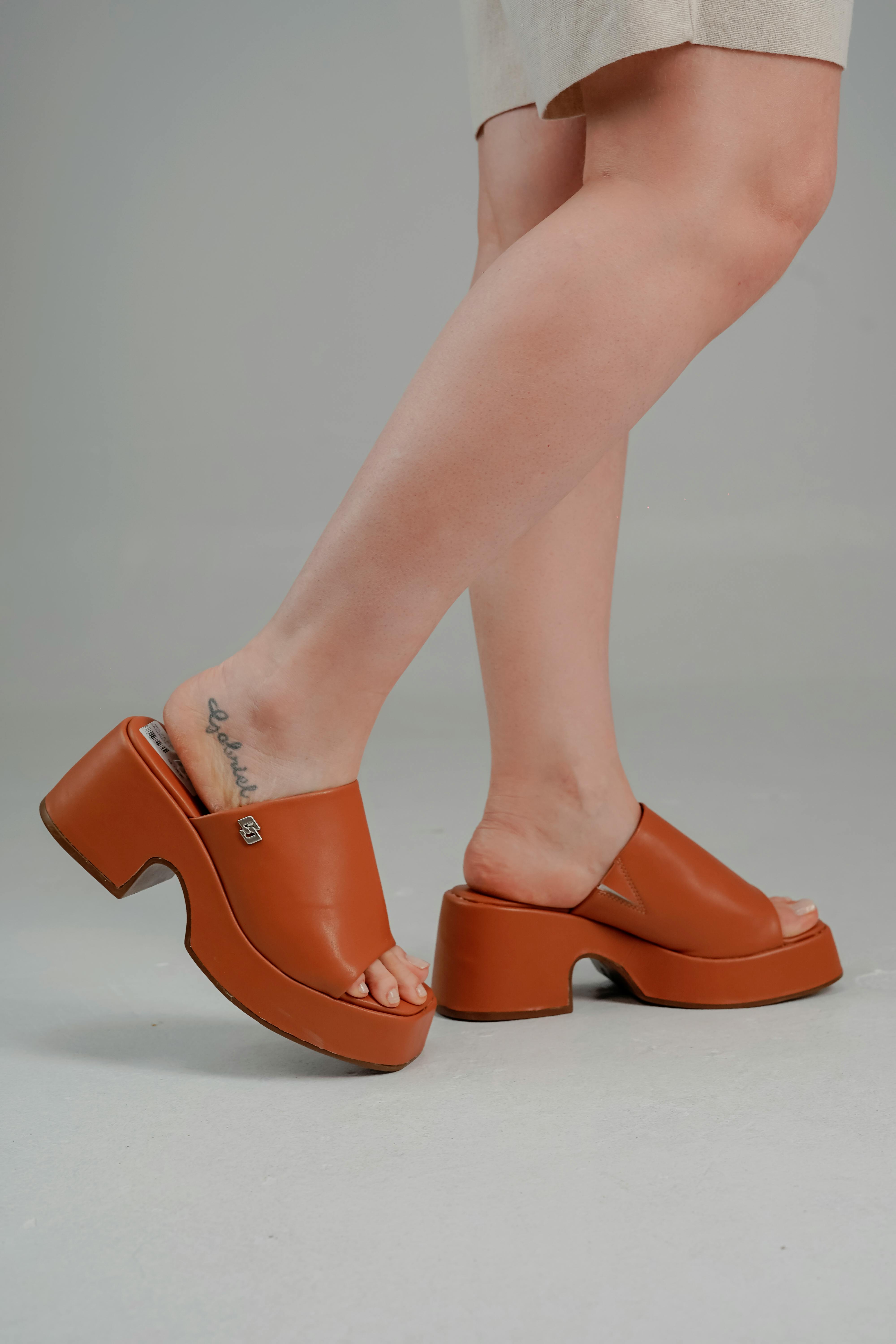 Trendy brown platform sandals worn by model with leg tattoo, perfect fashion statement.
