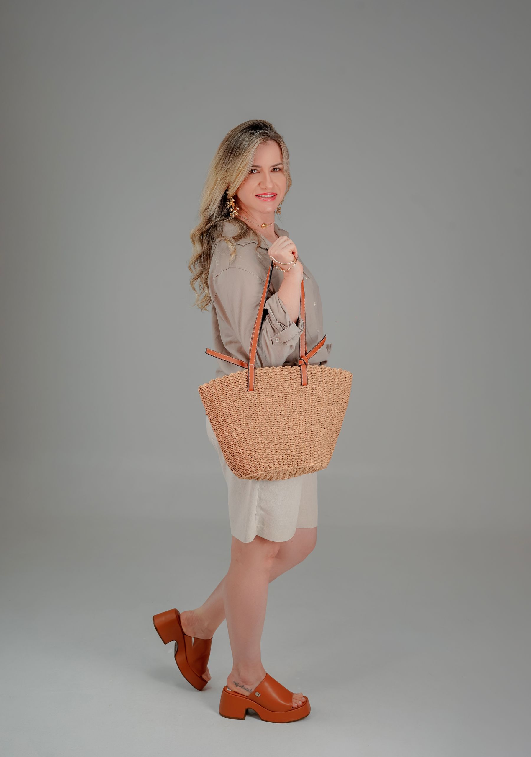 Woman in a neutral everyday outfit carrying a woven handbag as part of a refined styling look
