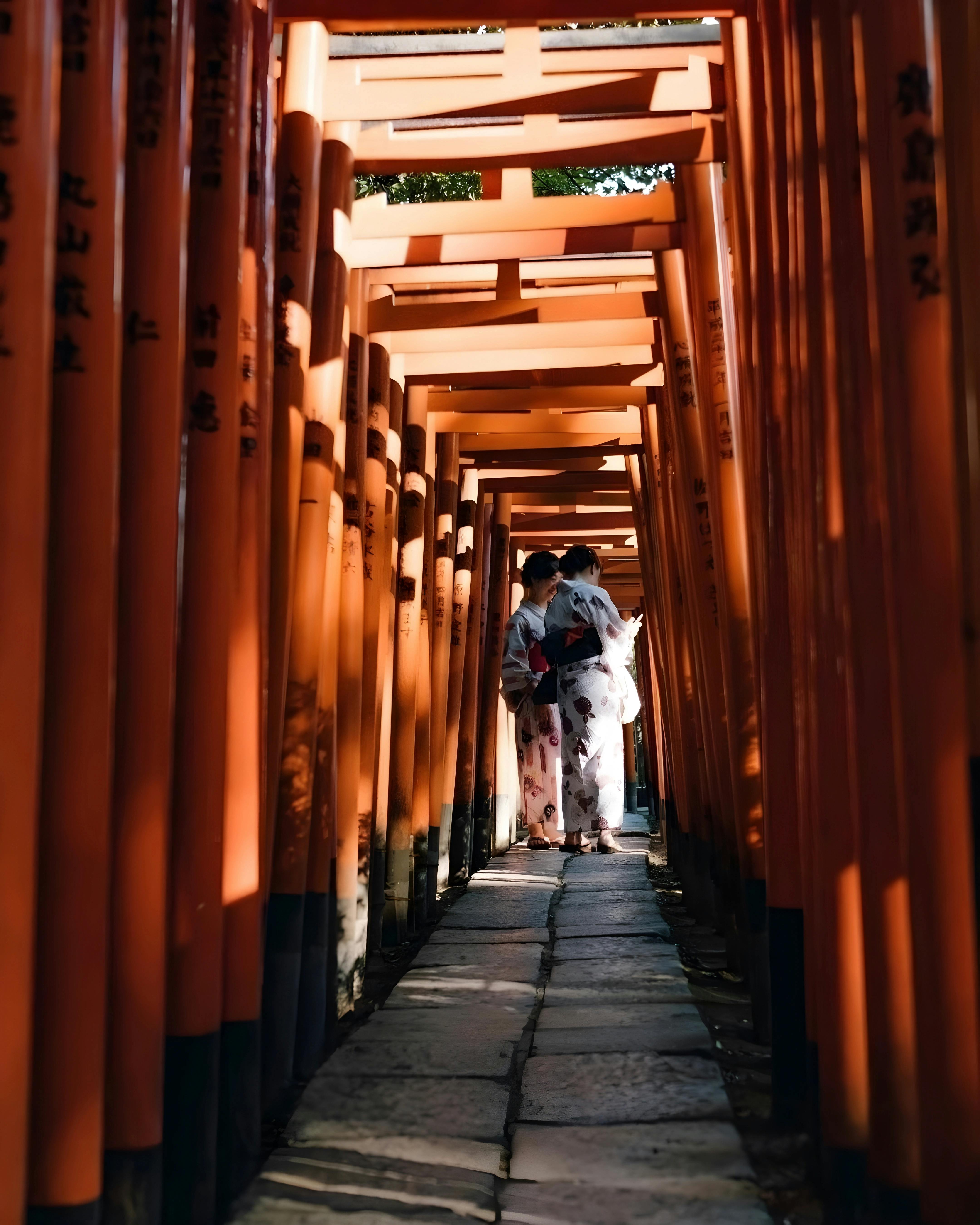 A couple in traditional kimono walking through Torii gates at Fushimi Inari, Kyoto.