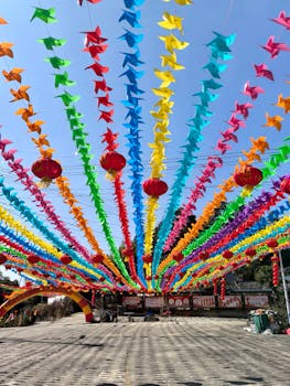 Vibrant pinwheels and lanterns decorate a festival area under a clear sky.