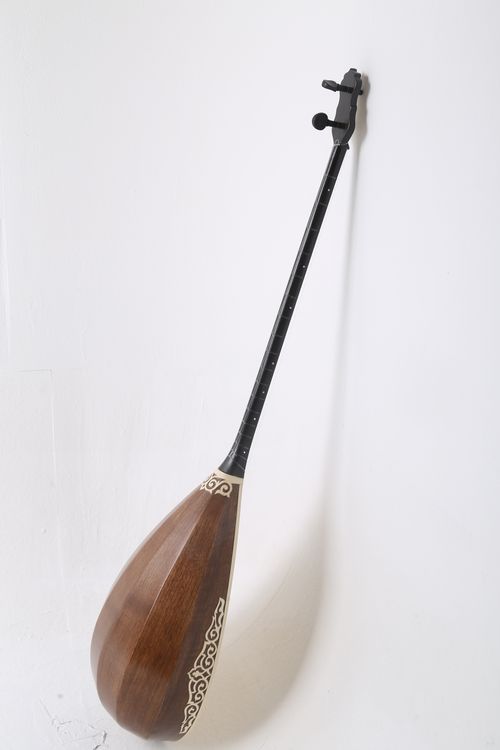 Free Traditional Kazakh dombyra with intricate design against a white wall. Stock Photo