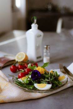 Plate of fresh salad with boiled eggs and edible flowers, perfect for a spring meal.