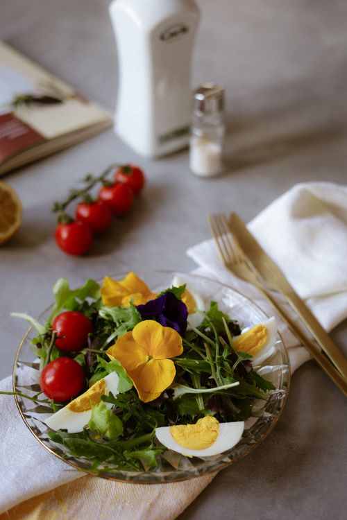 Free Healthy garden salad with tomatoes, greens, edible flowers, and boiled eggs on a table. Stock Photo