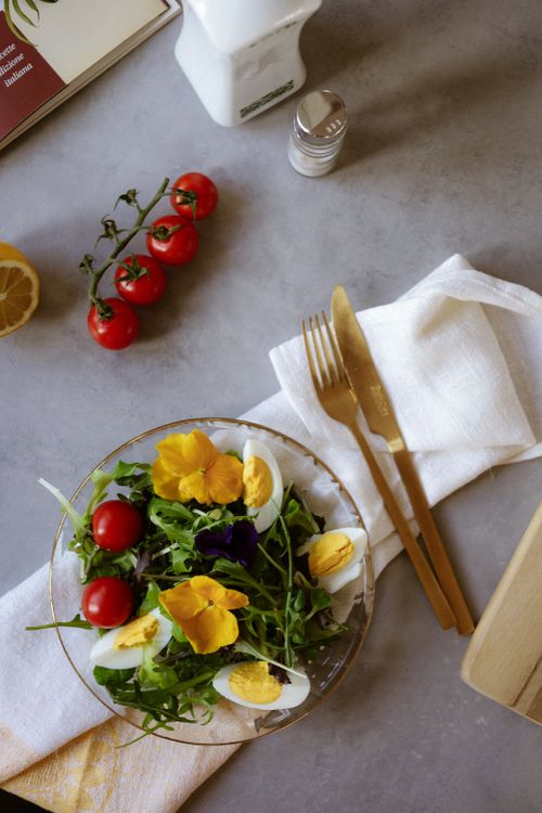 Free Aerial view of a vibrant salad with cherry tomatoes, eggs, and edible flowers on a table. Stock Photo