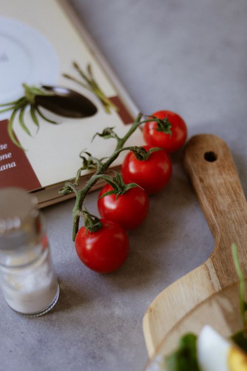 Free Cluster of ripe cherry tomatoes on a wooden cutting board, perfect for cooking inspiration. Stock Photo