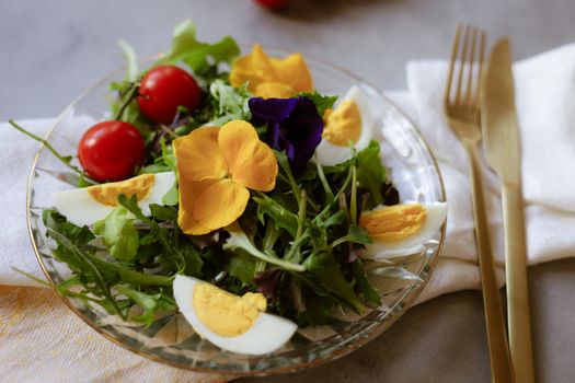 Healthy salad featuring edible flowers, cherry tomatoes, and hard-boiled eggs.