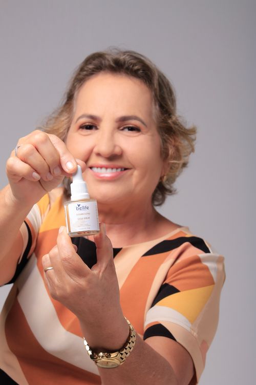 Free Elderly woman smiles while showing a skincare serum bottle, promoting beauty routines. Stock Photo