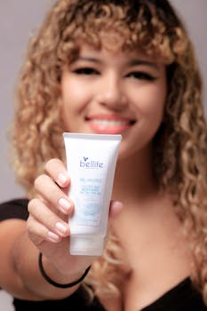 A woman smiles while holding a skincare product forward in focus.
