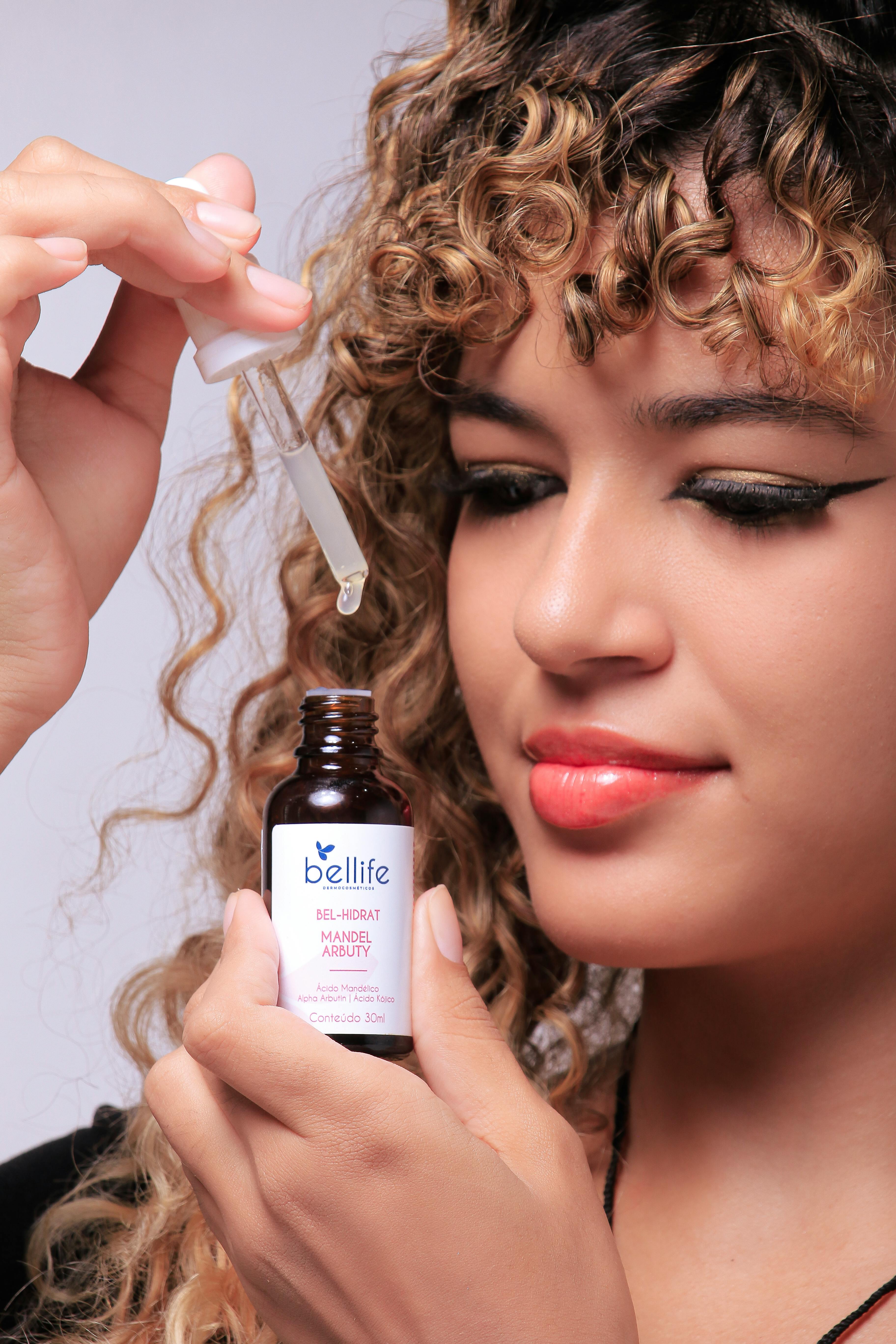 A young woman applies skincare serum with a dropper on her face, promoting beauty care.