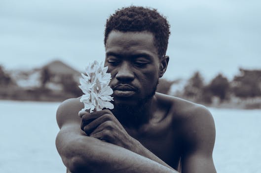 Thoughtful man holding flower in Ghana, embodying African art aesthetics.