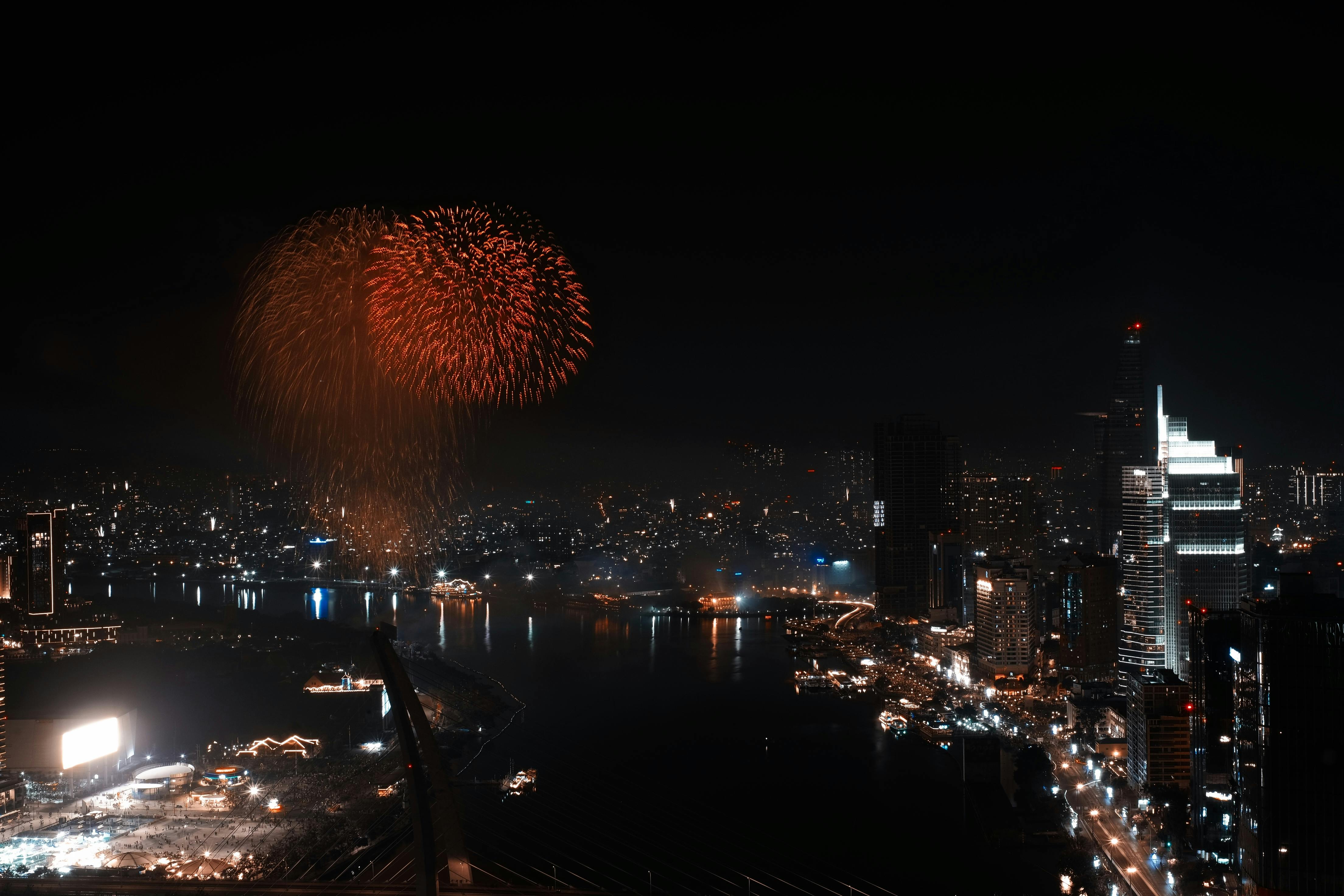 A stunning aerial view of fireworks illuminating the night sky above Ho Chi Minh City's skyline and river.