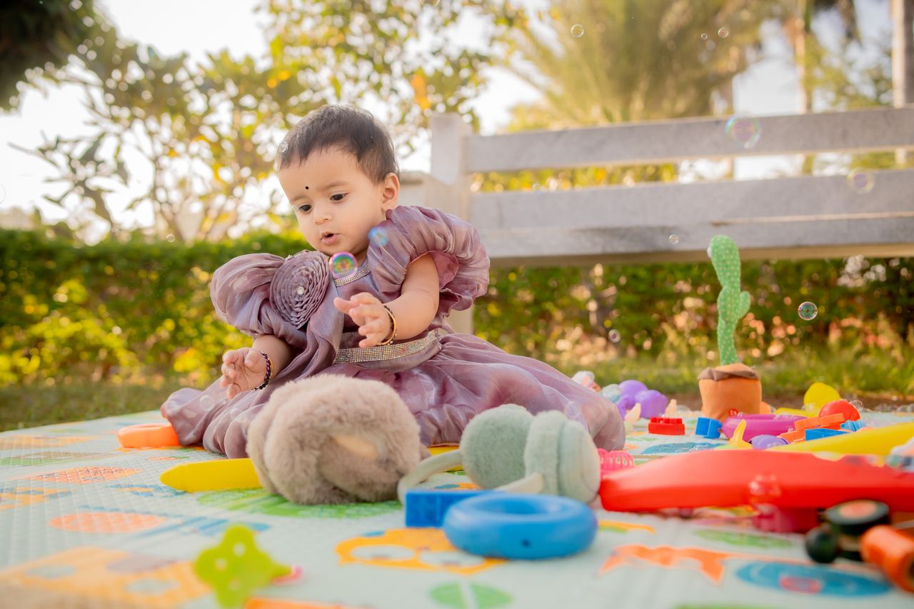adorable baby in a purple dress playing with colorful toys in a sunny