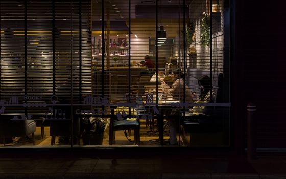 Nighttime view of a cozy Kyoto café illuminated with soft lighting, capturing a warm and inviting urban atmosphere.