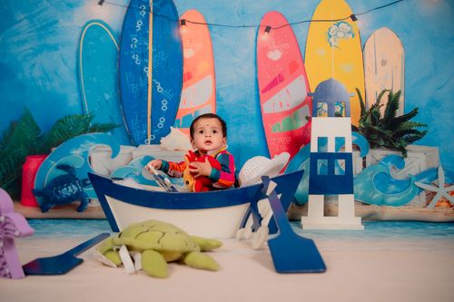 Free Cute baby in a boat-themed setup with colorful surfboards on a beach backdrop. Stock Photo