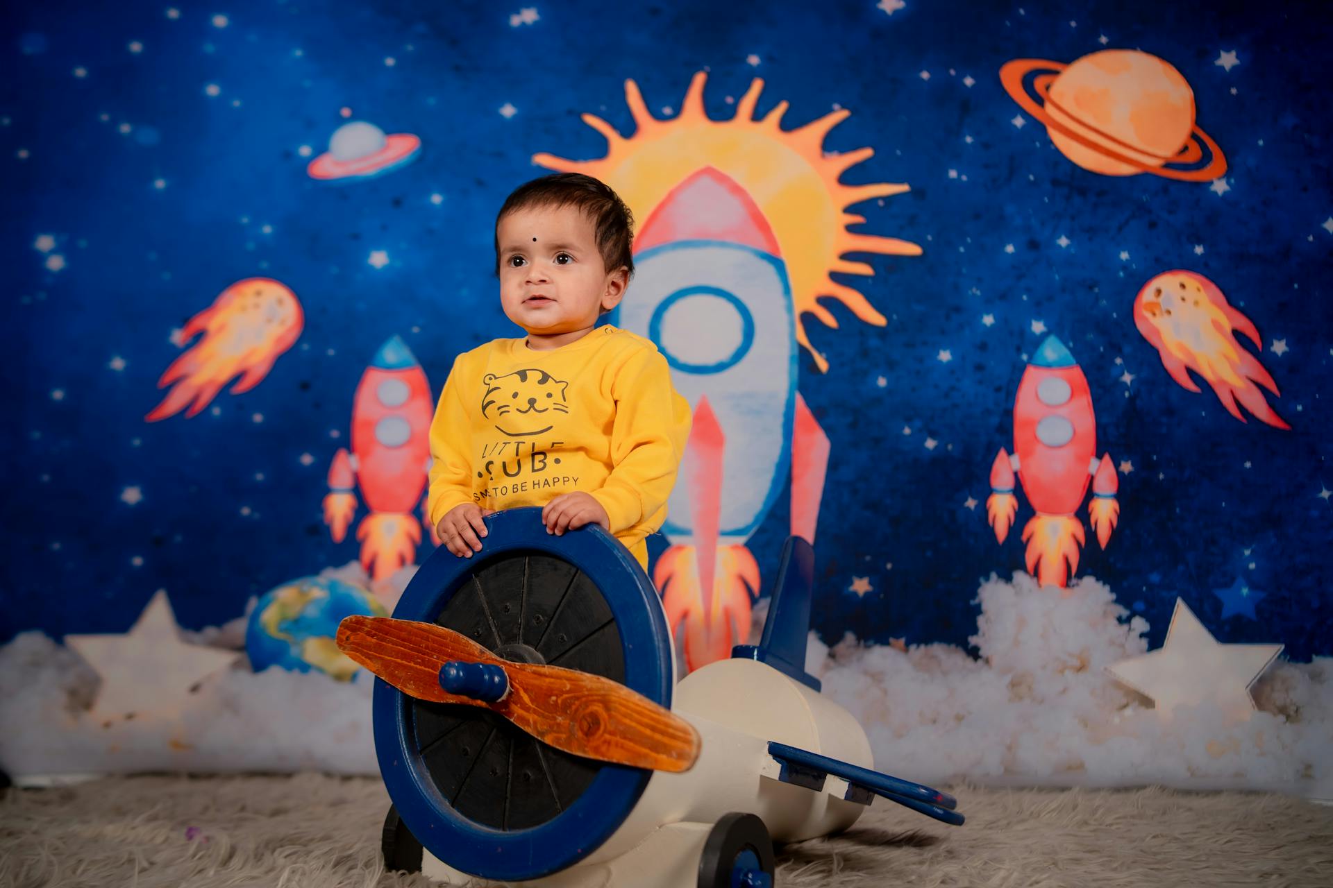 Adorable child enjoying playtime in a vibrant space-themed setting with rockets and stars.