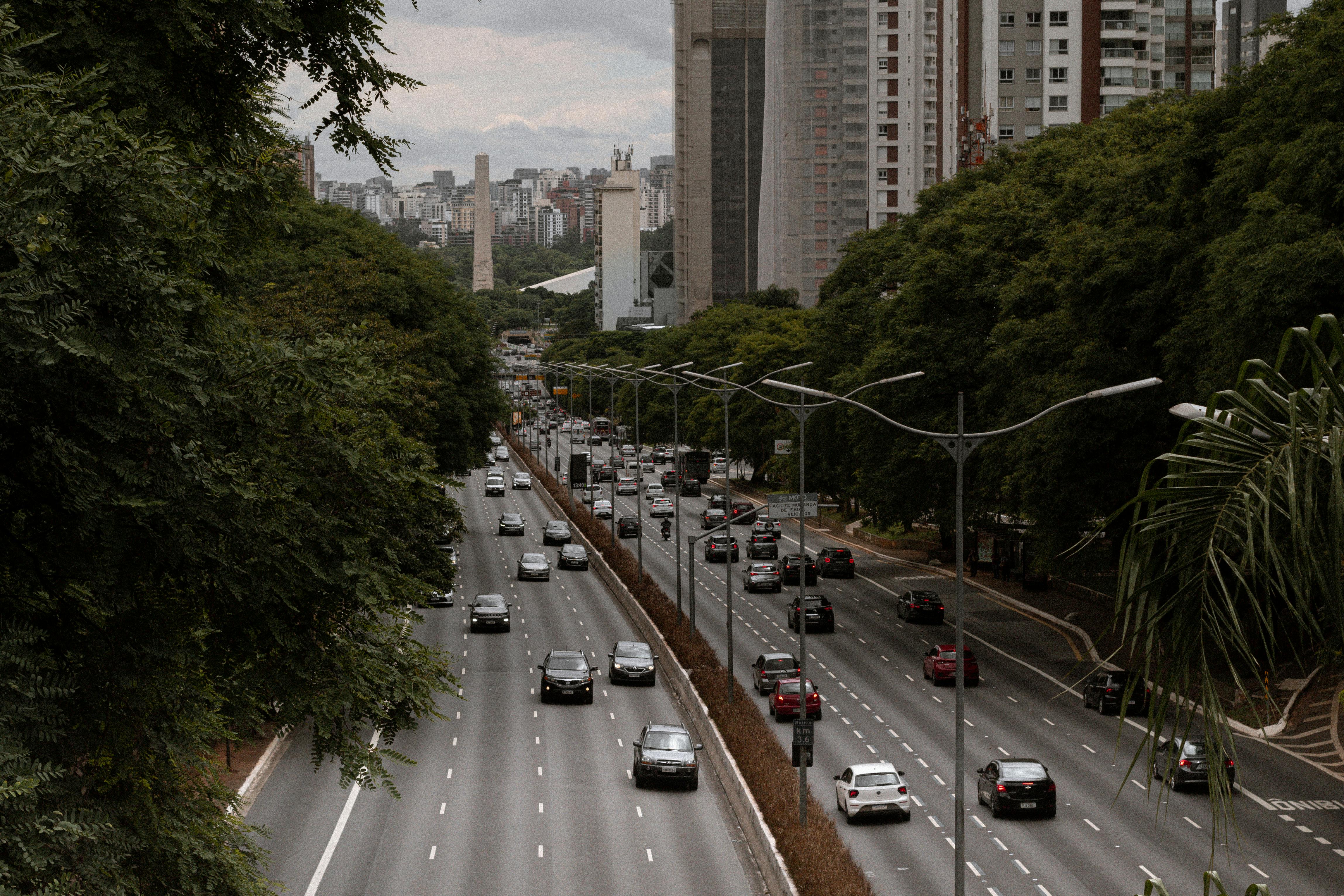 Rua movimentada de São Paulo com caminhões de mudança e trabalhadores manuseando caixas, foco em logística e trânsito
