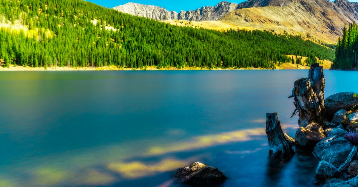 Tranquil mountain lake in Breckenridge, Colorado surrounded by lush forests and scenic landscapes.