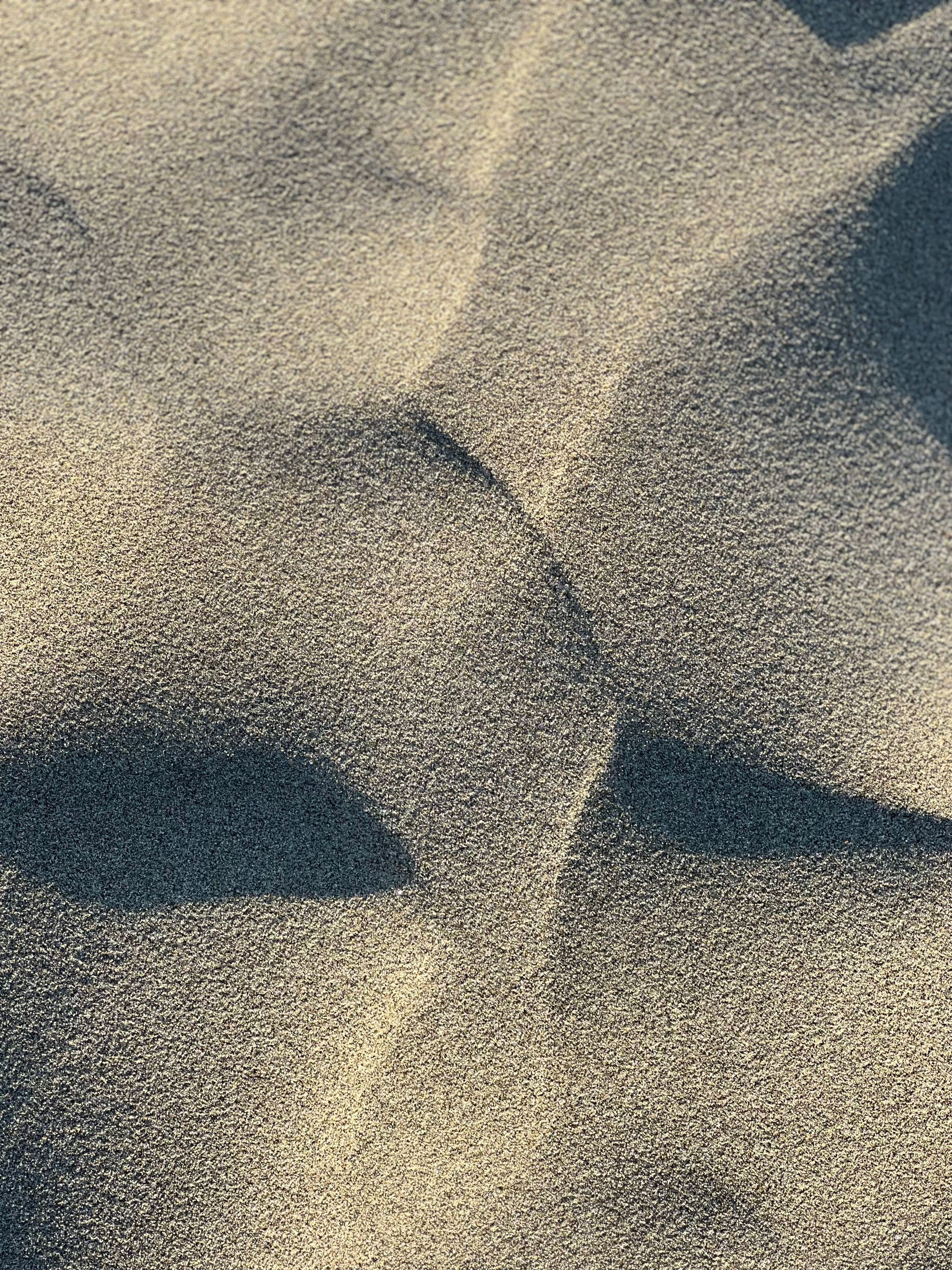 Fine sand formations create a textured surface on Cox's Bazar beach in Bangladesh, captured in close-up view.