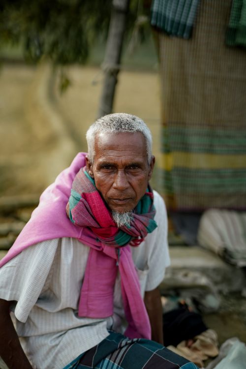 Free Portrait of an elderly man with a colorful scarf sitting outdoors. Stock Photo