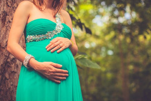 Zwangere Vrouw Die In Groene één Schouderkleding Haar Buik Houdt
