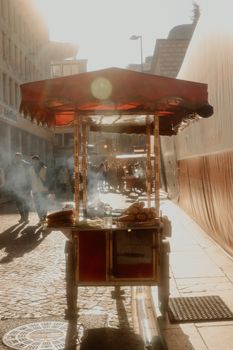 Sunlit street vendor in Istanbul selling roasted chestnuts to passersby.