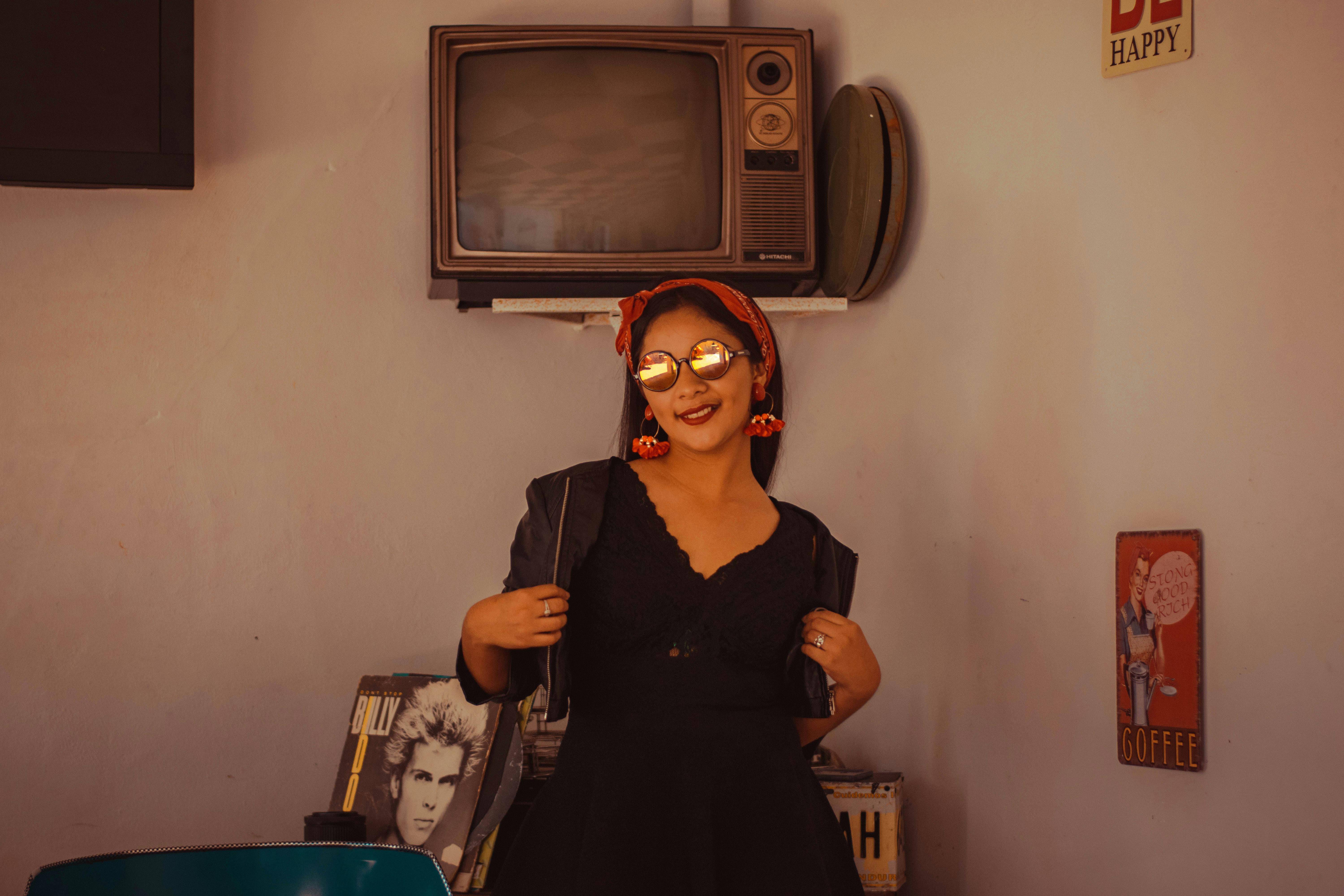 Woman in vintage outfit posing indoors with retro television.